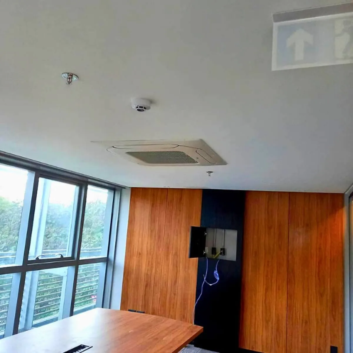 Sala com grandes vãos de vidro e cassete VRF no teto
